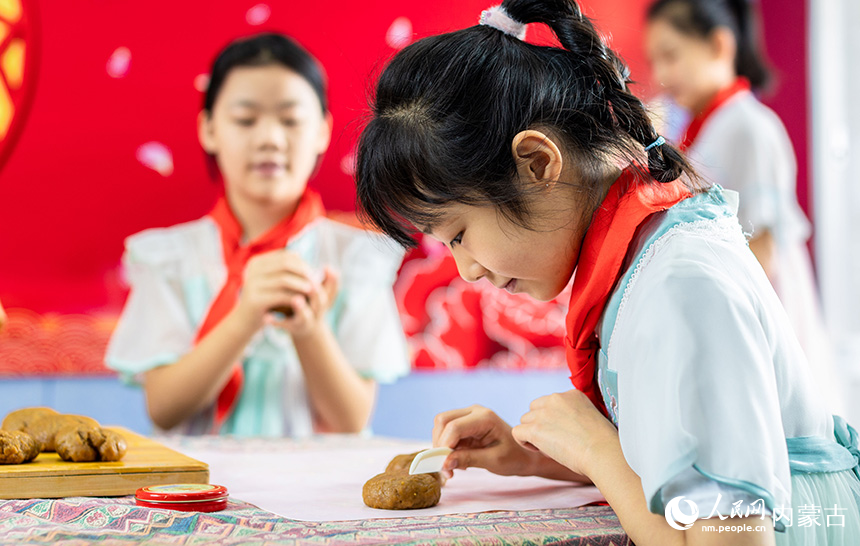 呼和浩特市玉泉區(qū)恒昌店巷小學(xué)學(xué)生在給自制的手工月餅印制花紋。丁根厚攝