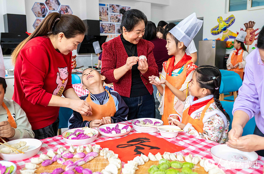 呼和浩特市玉泉區(qū)南柴火市街小學學生在家長的指導下體驗包餃子。丁根厚攝
