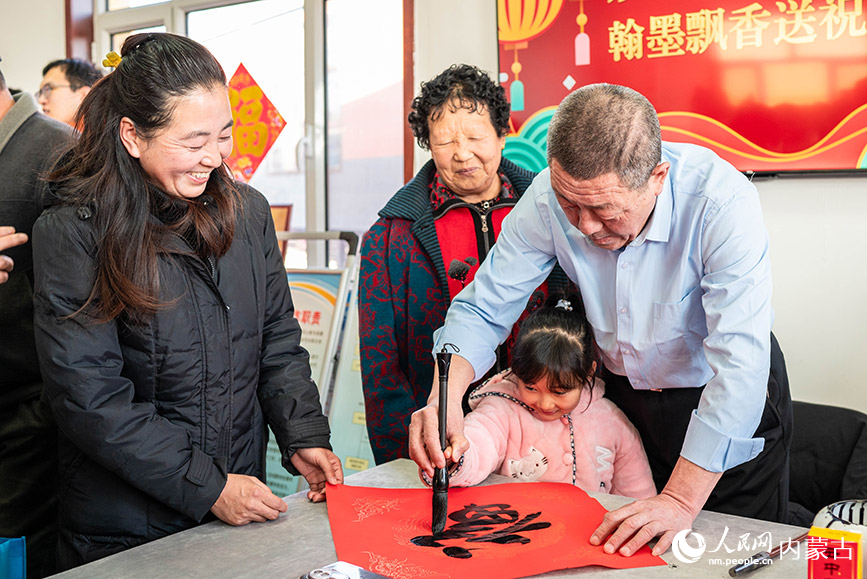 1月18日，志愿者在呼和浩特市玉泉區(qū)“三下鄉(xiāng)”活動現(xiàn)場教小朋友書寫新春福字。丁根厚攝