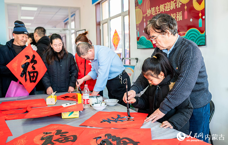 1月18日，志愿者在呼和浩特市玉泉“三下鄉(xiāng)”活動(dòng)現(xiàn)場教小朋友書寫春字。丁根厚攝