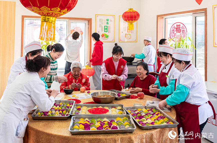 1月20日，志愿者與老人們在呼和浩特市玉泉區(qū)民政局迎新春主題活動現(xiàn)場一起包餃子。丁根厚攝