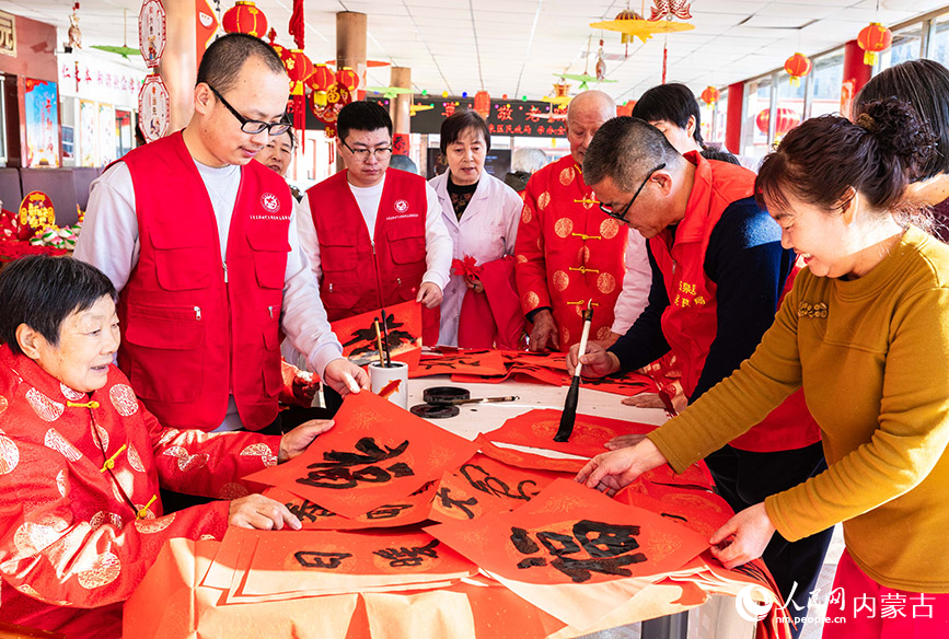 1月20日，文化志愿者在呼和浩特市玉泉區(qū)民政局迎新春主題活動現(xiàn)場為老人們書寫新春“福”字。丁根厚攝