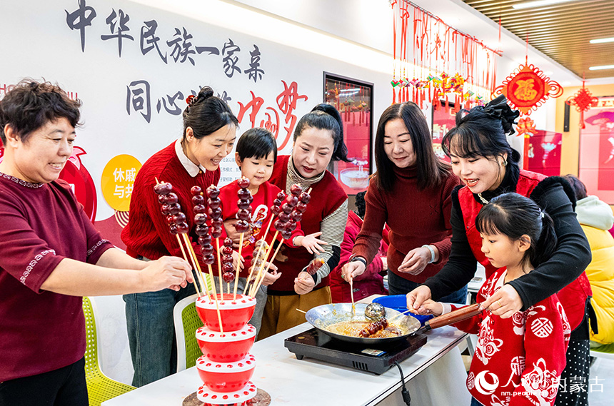 呼和浩特市玉泉區(qū)清泉街社區(qū)志愿者、居民在體驗制作冰糖葫蘆。丁根厚攝