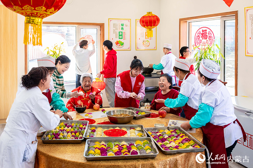 志愿者與老人們在呼和浩特市玉泉區(qū)民政局迎新春主題活動現(xiàn)場一起包餃子。丁根厚攝