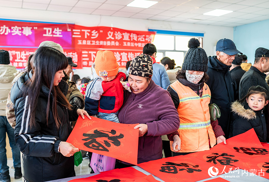 志愿者在呼和浩特市玉泉區(qū)前毛道村為群眾贈(zèng)送新春福字、春聯(lián)。丁根厚攝