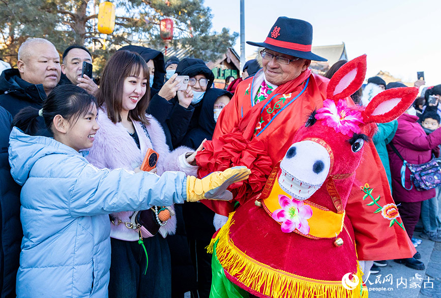 2025年2月3日，民間藝人在呼和浩特新春文化廟會(huì)上與游客互動(dòng)。丁根厚攝