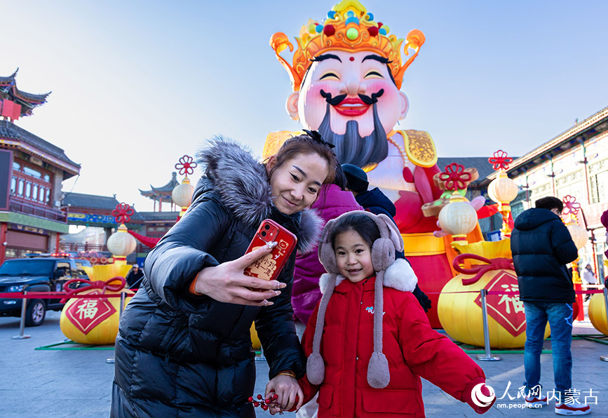2025年2月3日，游客在呼和浩特新春文化廟會活動(dòng)現(xiàn)場設(shè)置的財(cái)神花燈前留影。丁根厚攝